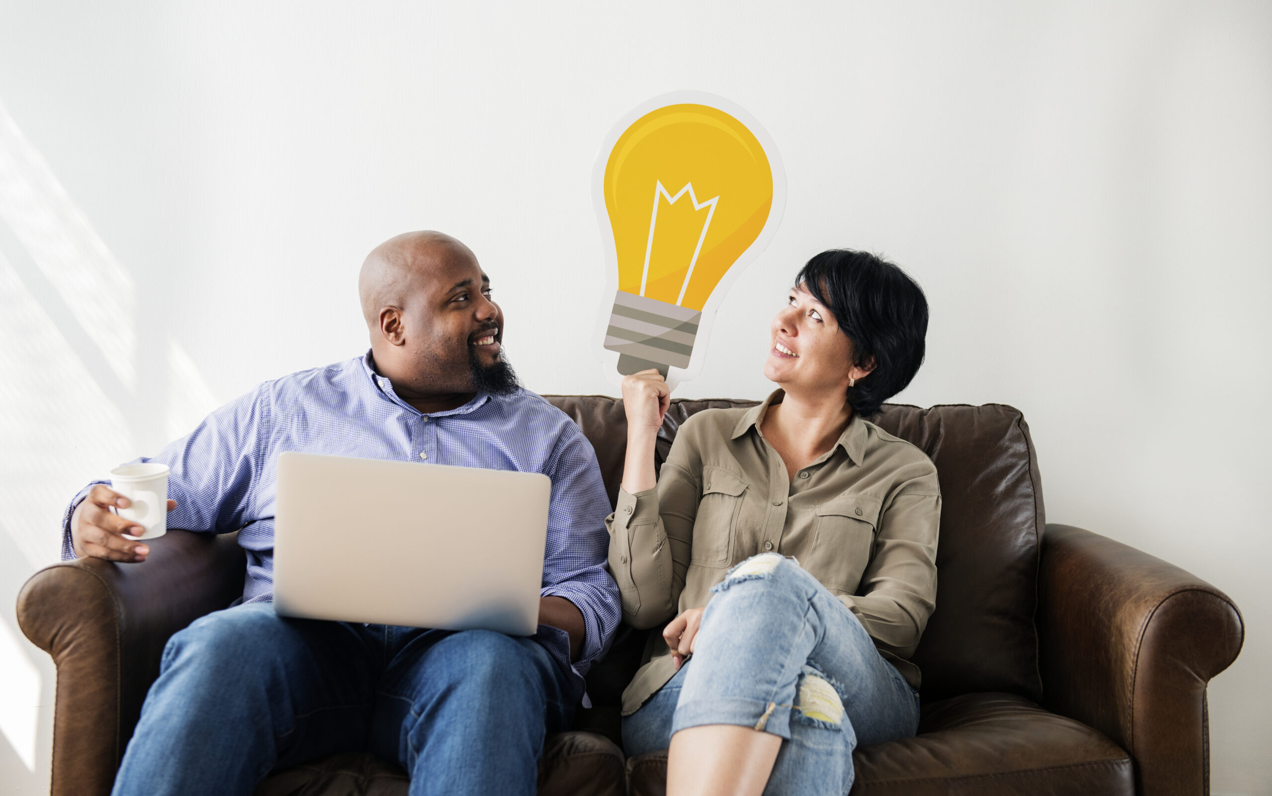 A lightbulb icon, representing Neuro-Linguistic Programming (NLP), personal growth, and innovative thinking, sits between two people on a couch as they exchange ideas.